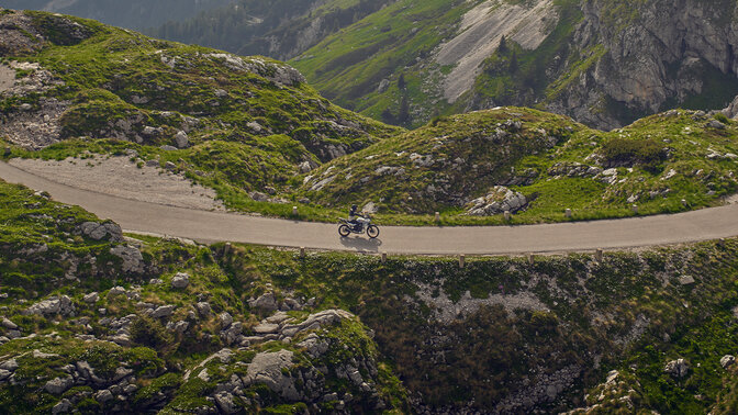 Model na motocyklu XL750 Transalp na silnici v horské lokalitě.