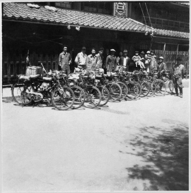 Řada 13 historických motocyklů Honda v Japonsku s lidmi stojícími za nimi